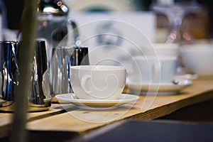 Two white porcelain cups for coffee on a wooden table. Shallow depth of field. Focus on the first cup