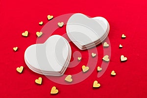 Two white porcelain hearts and many small hearts on a red background.