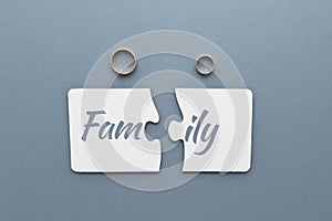 two white puzzles with the separated word family, two wedding rings on a gray-blue background,