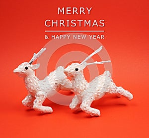 Two white reindeer decoration at red background with copy space for your own text