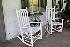 Two white rocking chairs on the porch,
