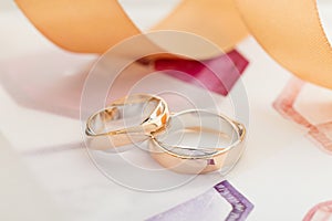 Two white and rose gold wedding rings on pastel background