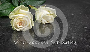 Two white roses on a dark background. With Deepest Sympathy text.