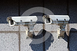 Two white security cameras on the concrete wall