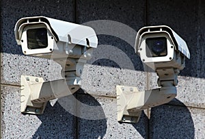 Two white security CCTV cameras on the wall