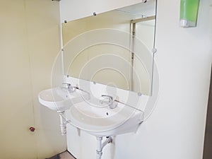 Two white sinks and mirror on the public toilet photo