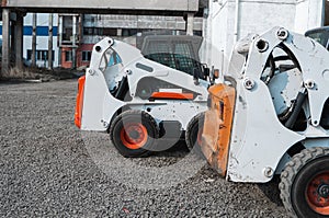 Two white skid steer loader at a construction site waiting of work. Industrial machinery. Industry.