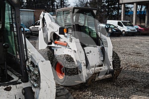 Two white skid steer loader at a construction site waiting of work. Industrial machinery. Industry.