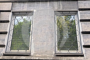 Two white windows with a iron lattice on a gray concrete wall