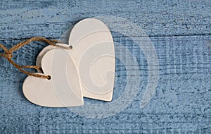 Two white wooden hearts on on a blue background.Valentine`s Day greeting card.Love,romantic or wedding concept with space for text