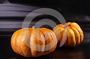 Two whole fresh orange big pumpkin on black background, closeup. Organic agricultural product, ingredients for cooking