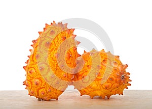 Two whole Kiwano fruit on wood table isolated