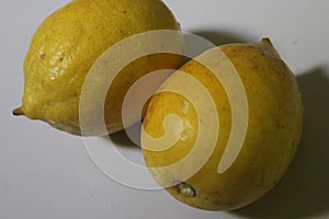 two whole lemons on a white background, one of the fruits that is rich in vitamin C