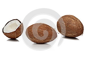 Two whole and one cut half coconuts with shadow on white background