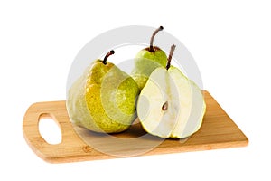 Two whole and one half sliced Green Anjou pears on wooden chopping board, isolated on white background