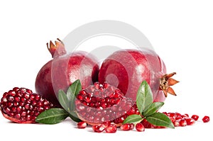 Two whole and part of a pomegranate with pomegranate seeds