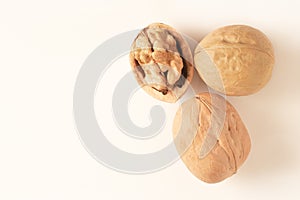 Two whole walnuts and one split walnut on white background with free space