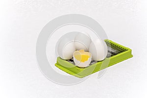 Broken and whole white eggs on green kitchen cutter on a white surface