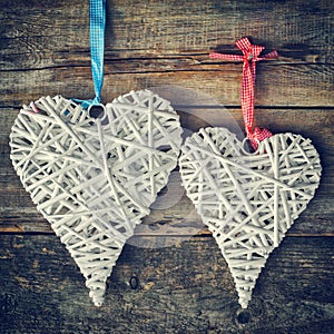 Two wicker hearts hanging on old wooden wall.