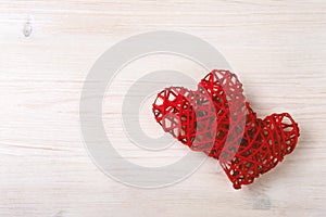 Two wicker red hearts on the wooden background.