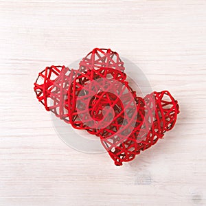 Two wicker red hearts on the wooden background.
