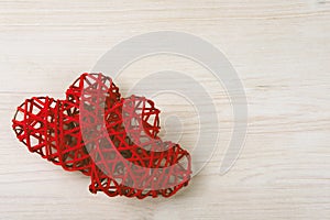 Two wicker red hearts on the wooden background.