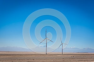 Two wind mills with volcanos in the background in Atacama Desert in Chile