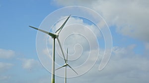 Two Wind Turbines against a blu summer sky with some clouds on a windy day in East Frisia, Lower Saxony, Germany. 2023