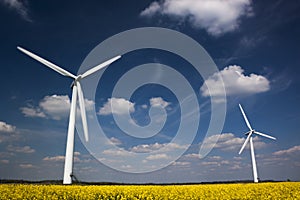 Two Wind Turbines against a blue, cloud-strewn sky