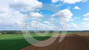 Two wind turbines in the middle of barley and flax fields