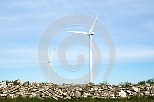 Two wind turbines by an old traditional stonewall at the swedish