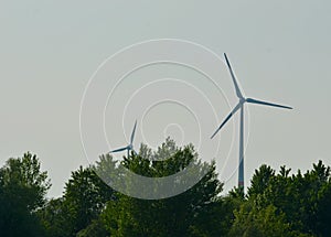 Two wind turbines surrounded by trees