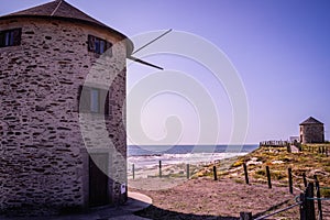 Two windmills on the dunes of ApÃºlia beach with a wooden fence and cordon delineating the walkway, Esposende PORTUGAL