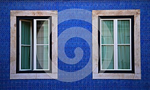 Two windows on a blue wall in Lisbon, Portugal. Horizontal