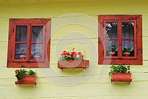 Two windows on the facade of ancient wooden yellow house