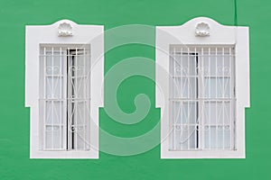 Two windows on a green facade of an old house