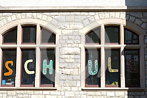 Two windows with letters saying school in German language visible from outside.