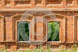 Two windows of the old destroyed building of red brick through w