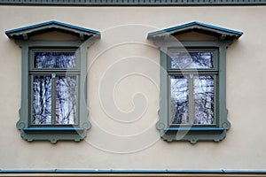 Two windows in an old house in a city park. Beautiful platbands and reflection in glasses.