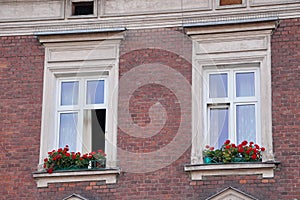 Two Windows in an old house, decorated with flowers windowsill. renovated facade of the slopes. the walls are of red brick