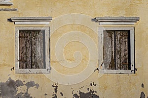 Two windows in old wall with closed brown shutters, Pellestrina island, Venetian lagoon, Italy