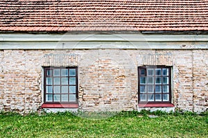 Two windows on old wall with lawn and roof