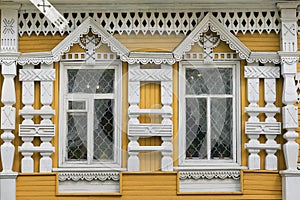 Two windows of an old wooden house in traditional folk Russian style decorated with wood carving.