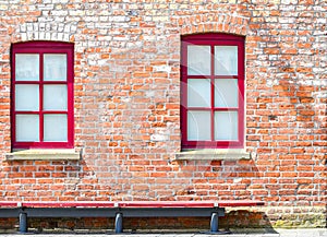 Two windows with red frames in a brick wall