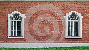 Two windows in a row on brick wall of old house.