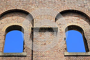 Two arched windows in ruin towards blue sky