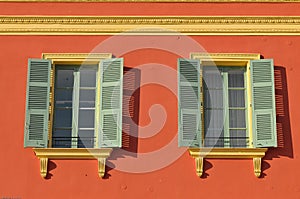 Two windows with window shades open on a red wall