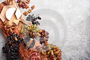 Two Wine bottles with grapes, slice cheese camembert, nut and wineglasses on old gray concrete table background with copy space.