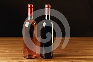 Two wine bottles on wooden table and black background