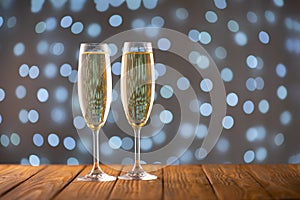 Two wine glasses with bubbly Champagne on blurry sparkling lights background